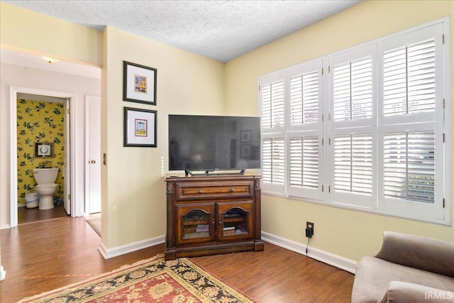 living area featuring baseboards, a textured ceiling, and wood finished floors