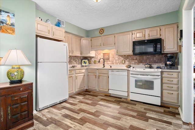 kitchen with light countertops, decorative backsplash, light wood-style flooring, white appliances, and a sink