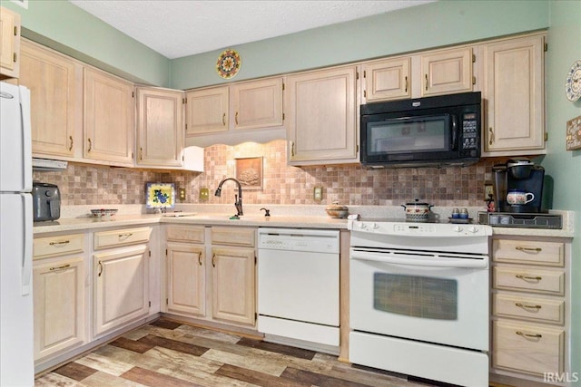 kitchen with white appliances, light wood finished floors, a sink, decorative backsplash, and light countertops