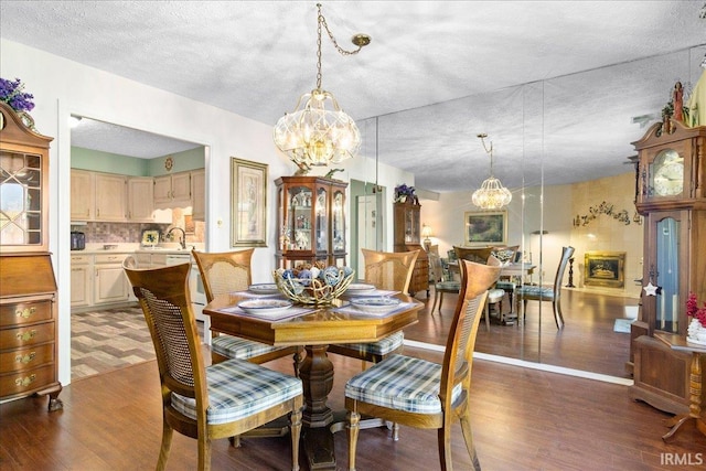 dining room featuring a notable chandelier, wood finished floors, and a textured ceiling