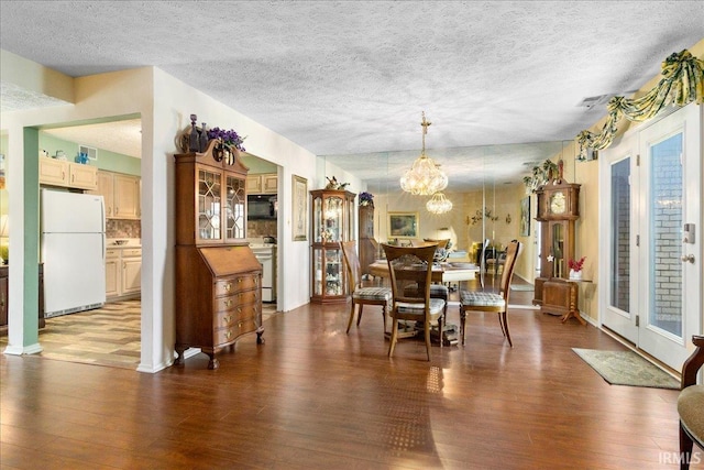 dining space with a notable chandelier, wood finished floors, and a textured ceiling