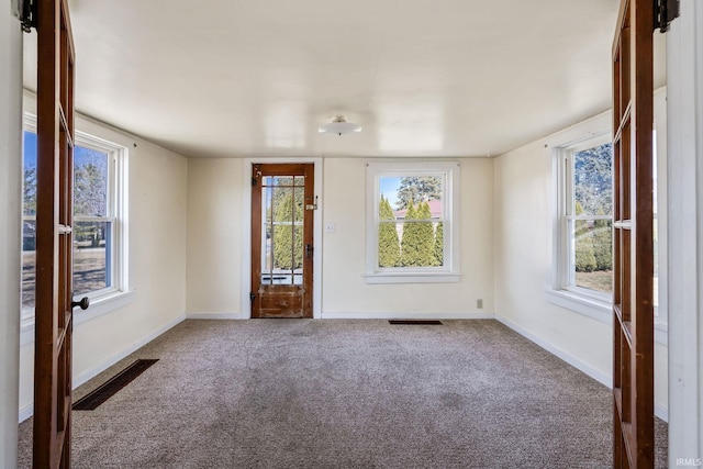 empty room featuring carpet flooring, baseboards, and visible vents