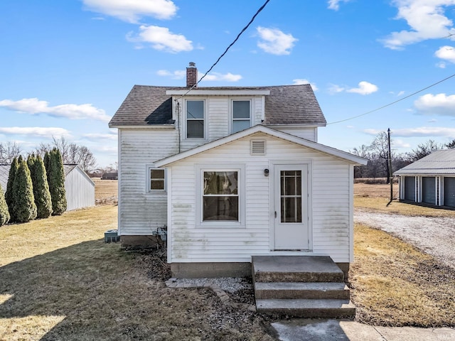 rear view of house with a chimney and a shingled roof