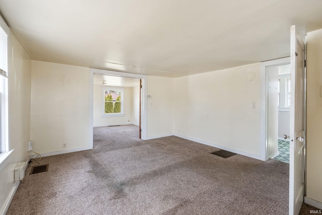 carpeted empty room featuring baseboards and visible vents