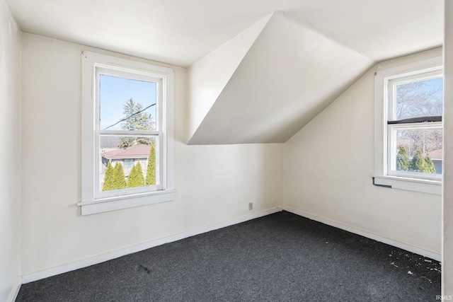 bonus room with a wealth of natural light, baseboards, lofted ceiling, and dark colored carpet