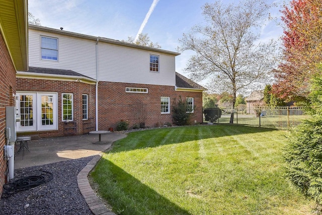 rear view of house featuring a patio, a yard, fence, and brick siding