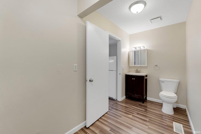 bathroom featuring visible vents, toilet, wood finished floors, baseboards, and vanity