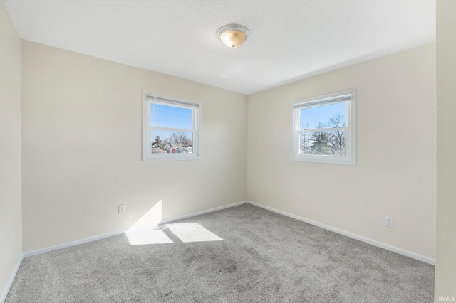 carpeted spare room featuring baseboards