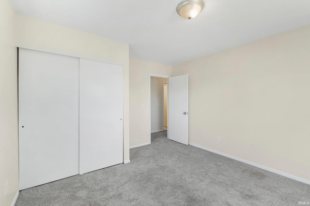 unfurnished bedroom with carpet, a closet, and baseboards