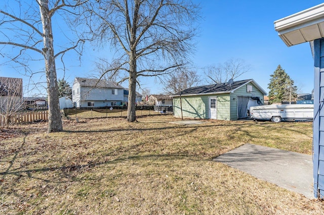 view of yard featuring a garage, a residential view, an outbuilding, and fence