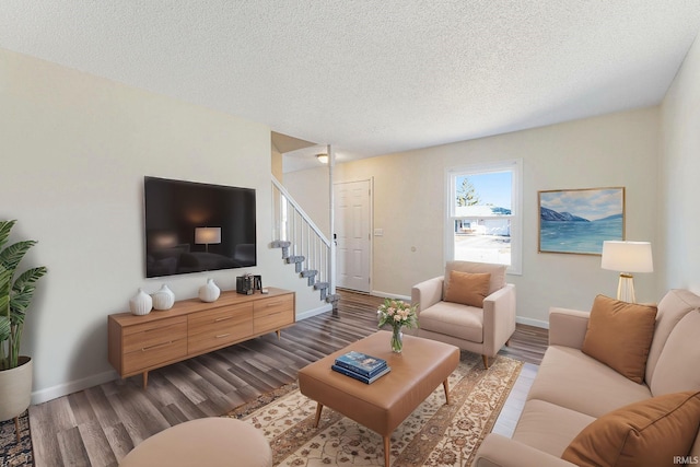 living area featuring stairway, wood finished floors, baseboards, and a textured ceiling