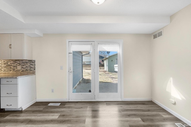 unfurnished dining area with wood finished floors, visible vents, and baseboards