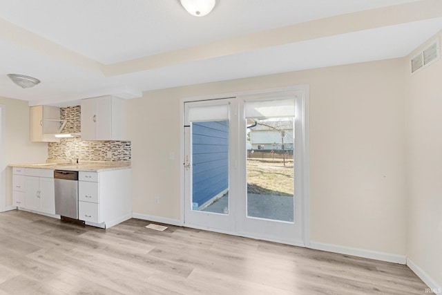 kitchen featuring visible vents, backsplash, light countertops, light wood-type flooring, and stainless steel dishwasher