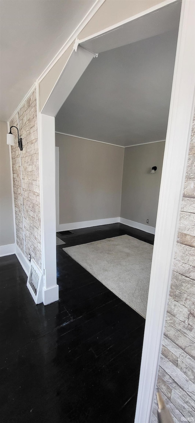 additional living space with baseboards, wood finished floors, and vaulted ceiling