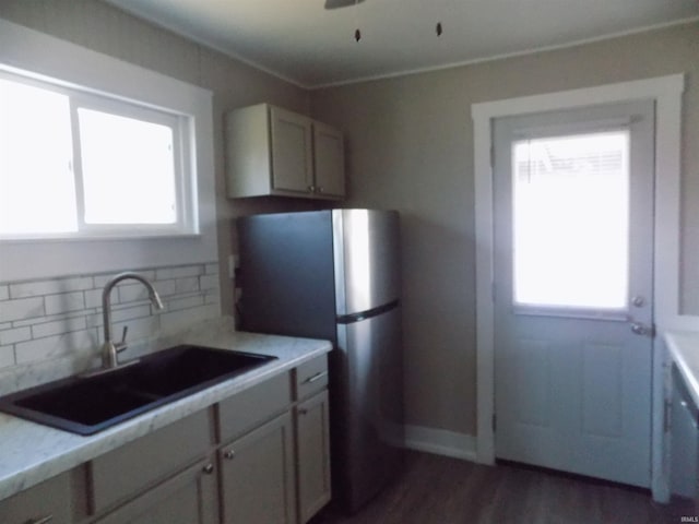 kitchen with dark wood-type flooring, a sink, freestanding refrigerator, light countertops, and decorative backsplash