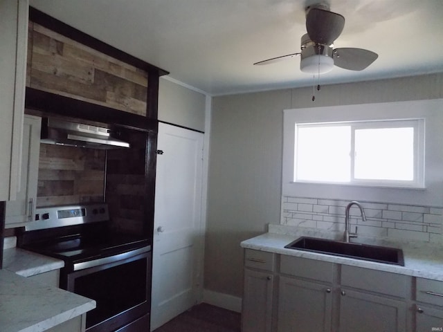 kitchen featuring tasteful backsplash, under cabinet range hood, stainless steel electric stove, a ceiling fan, and a sink