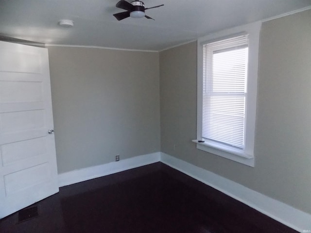 empty room with crown molding, baseboards, and ceiling fan