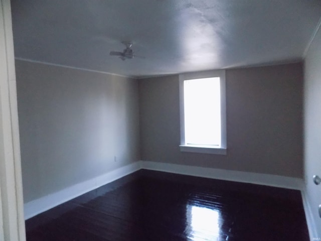 spare room featuring baseboards and dark wood finished floors