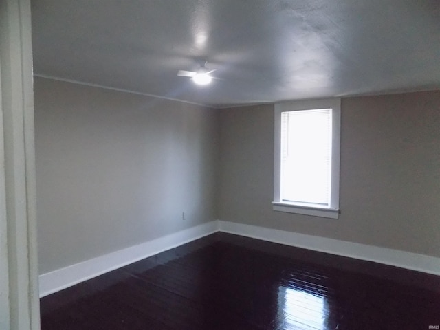 empty room with a ceiling fan, dark wood-type flooring, and baseboards