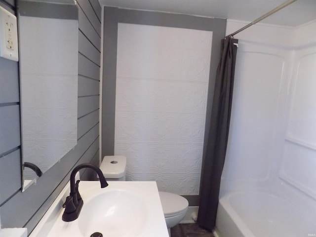 bathroom featuring a sink, shower / bathtub combination with curtain, and toilet