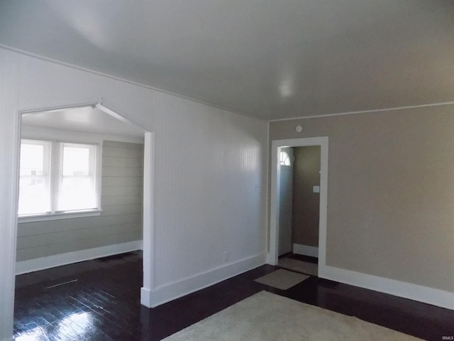 spare room with dark wood-type flooring and baseboards