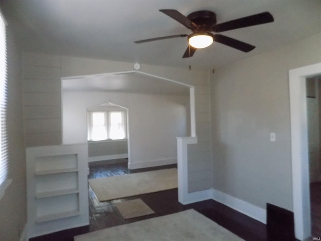 unfurnished room featuring baseboards, dark wood-type flooring, and ceiling fan