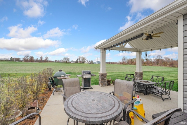 view of patio / terrace with outdoor dining space, a rural view, a grill, and a fire pit