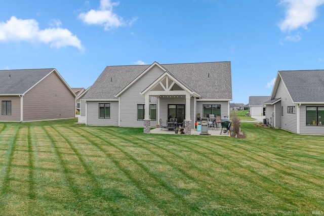 back of house with central air condition unit, a yard, a patio area, and a shingled roof