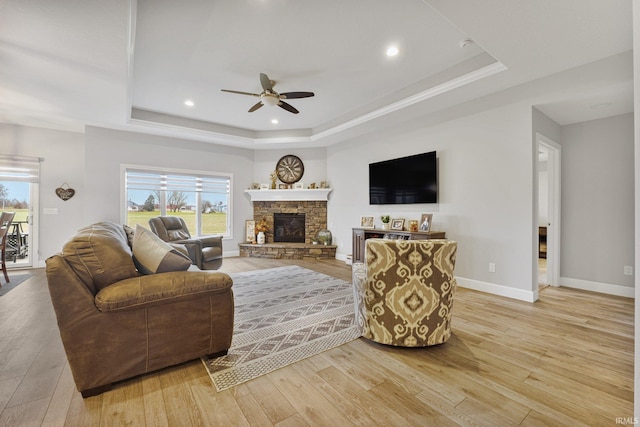 living room with a tray ceiling, light wood-style floors, and ceiling fan