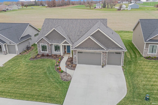 craftsman-style house featuring stone siding, driveway, an attached garage, and a front yard