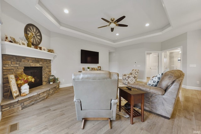 living room with a tray ceiling, baseboards, light wood-type flooring, and ceiling fan