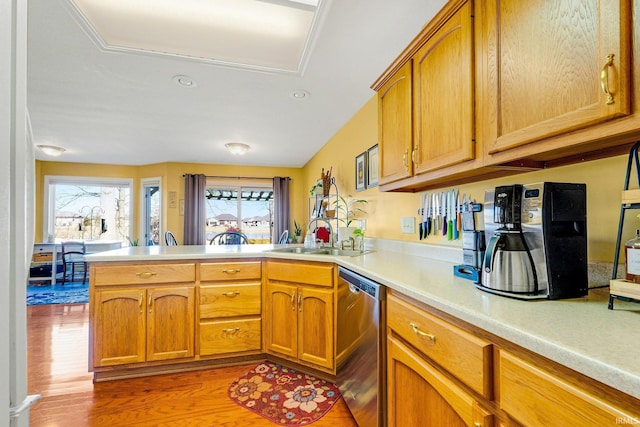 kitchen with light wood-style flooring, a sink, a peninsula, light countertops, and dishwasher