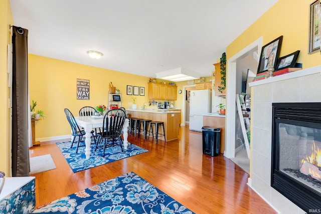 dining room with baseboards, light wood-style floors, and a fireplace