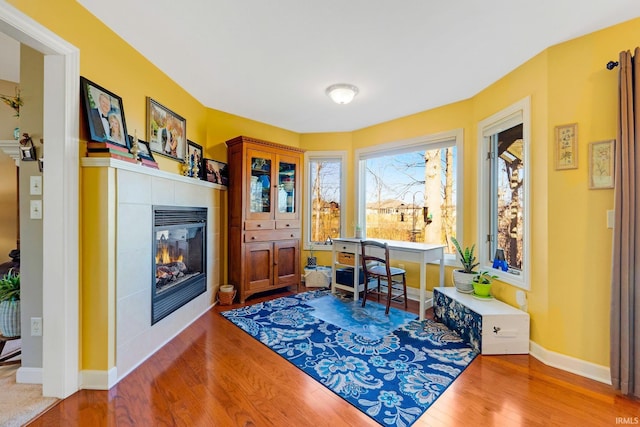 office featuring baseboards, wood finished floors, and a tile fireplace