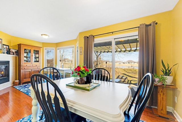 dining room featuring a fireplace, baseboards, and wood finished floors