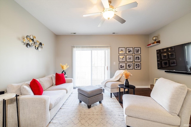 living area with baseboards, ceiling fan, and wood finished floors