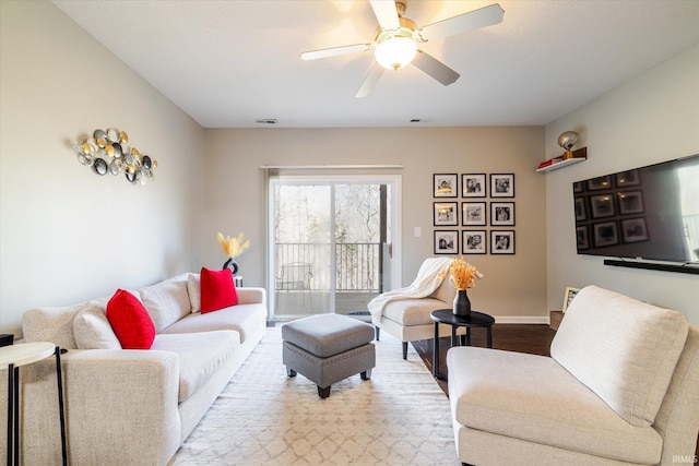 living area featuring visible vents, baseboards, a ceiling fan, and wood finished floors