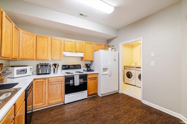 kitchen with white appliances, dark wood-style floors, light countertops, under cabinet range hood, and washing machine and dryer