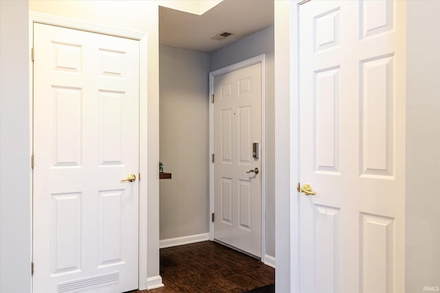 corridor with visible vents, dark wood-type flooring, and baseboards