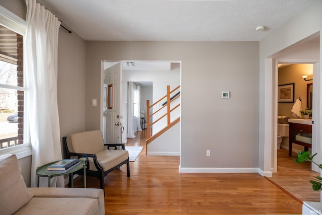 sitting room with stairway, baseboards, and light wood-type flooring