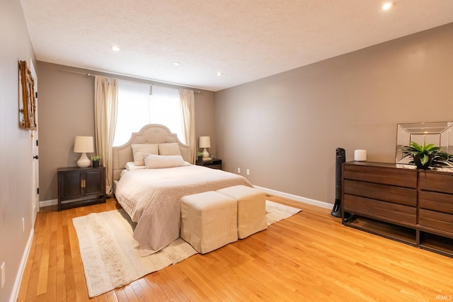 bedroom with recessed lighting, baseboards, wood-type flooring, and a textured ceiling