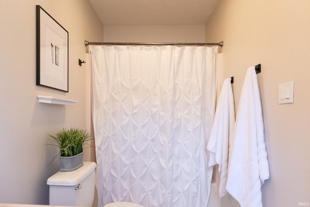 bathroom with toilet and a shower with curtain