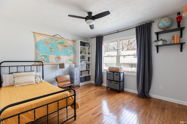 bedroom featuring light wood finished floors, ceiling fan, a textured ceiling, and baseboards