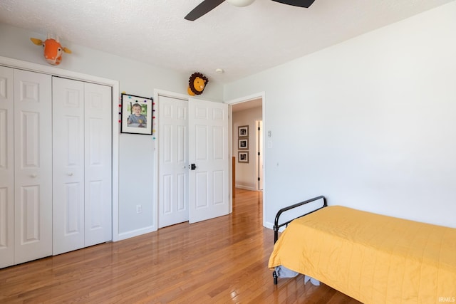 bedroom with light wood-style flooring, a ceiling fan, baseboards, and a textured ceiling