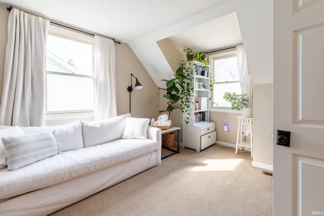 living area featuring visible vents, baseboards, lofted ceiling, and carpet floors