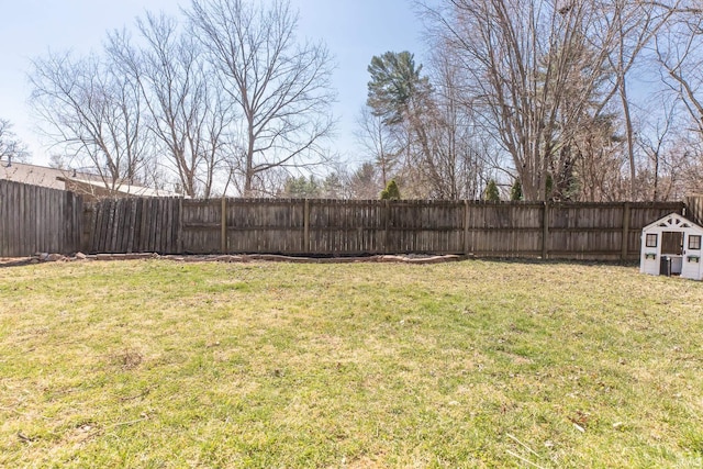 view of yard with an outbuilding, a fenced backyard, and a shed