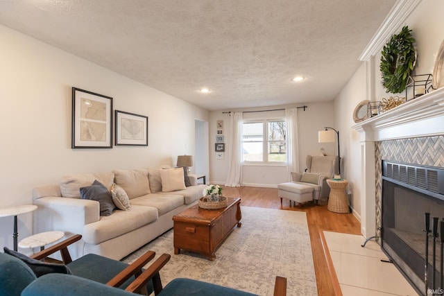 living area with recessed lighting, light wood-style floors, baseboards, and a textured ceiling