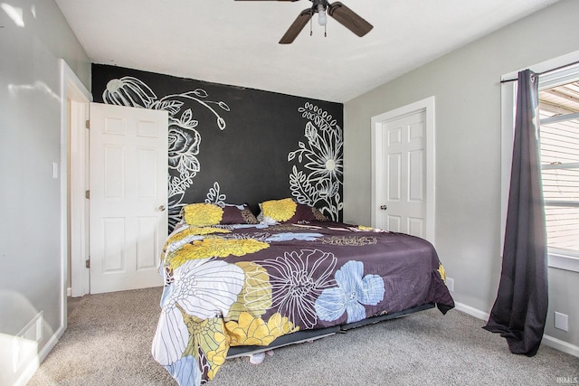 bedroom featuring an accent wall, carpet, baseboards, and ceiling fan