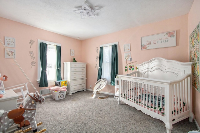 bedroom with visible vents, a nursery area, baseboards, and carpet