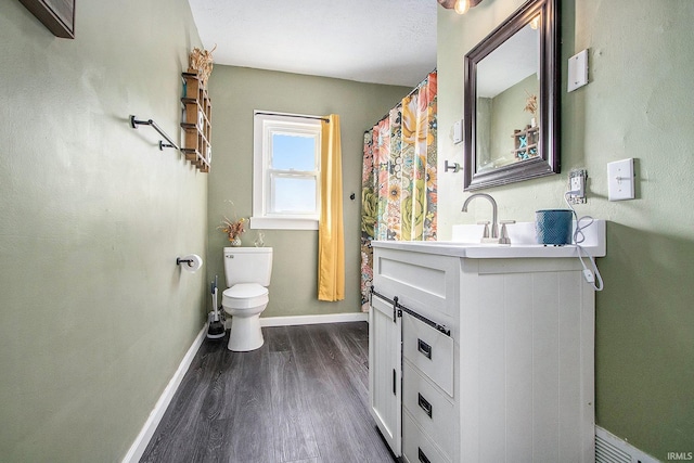 bathroom with baseboards, toilet, wood finished floors, and vanity